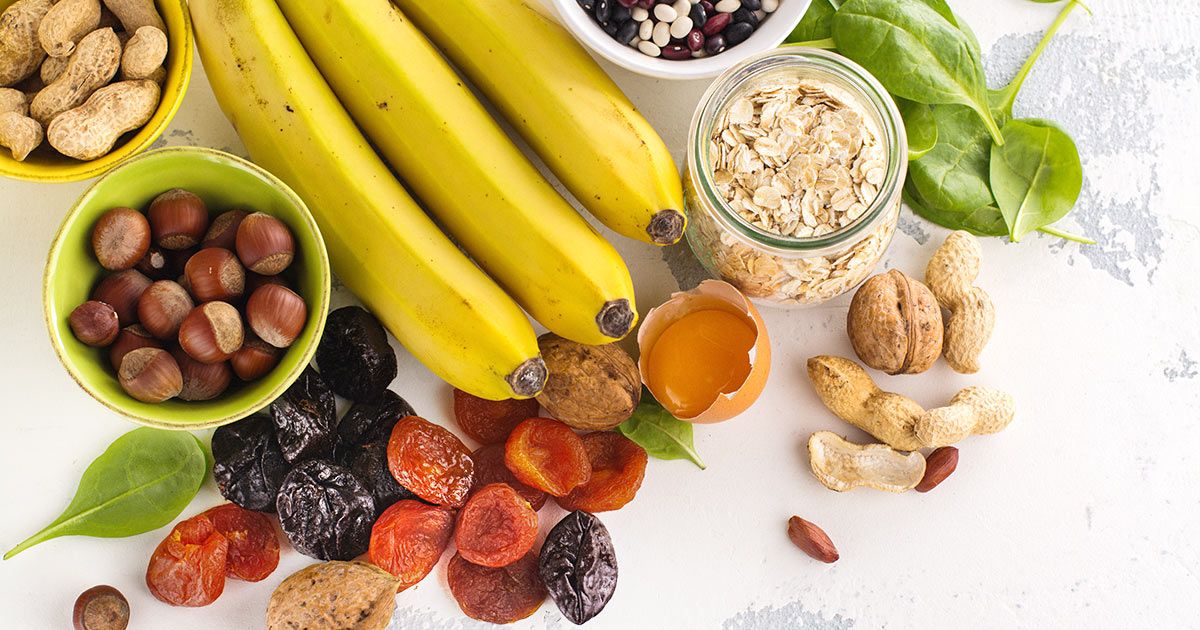 Bananas, nuts, dried fruit, oats, beans and spinach on a table